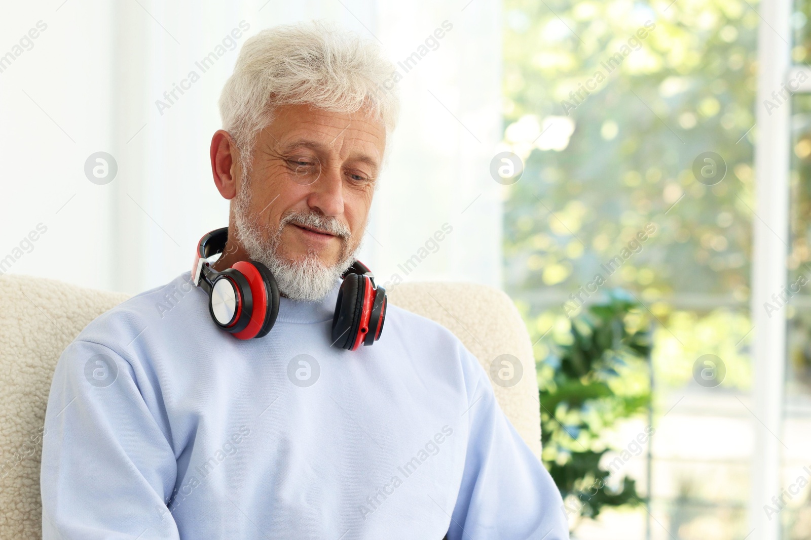 Photo of Senior man with headphones at home, space for text