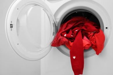 Photo of Washing machine with laundry near light wall, closeup