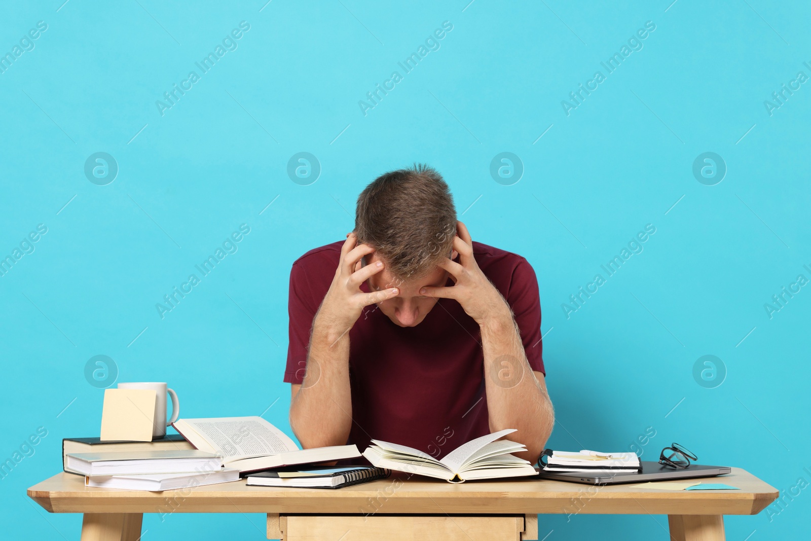 Photo of Student preparing for exam at table against light blue background