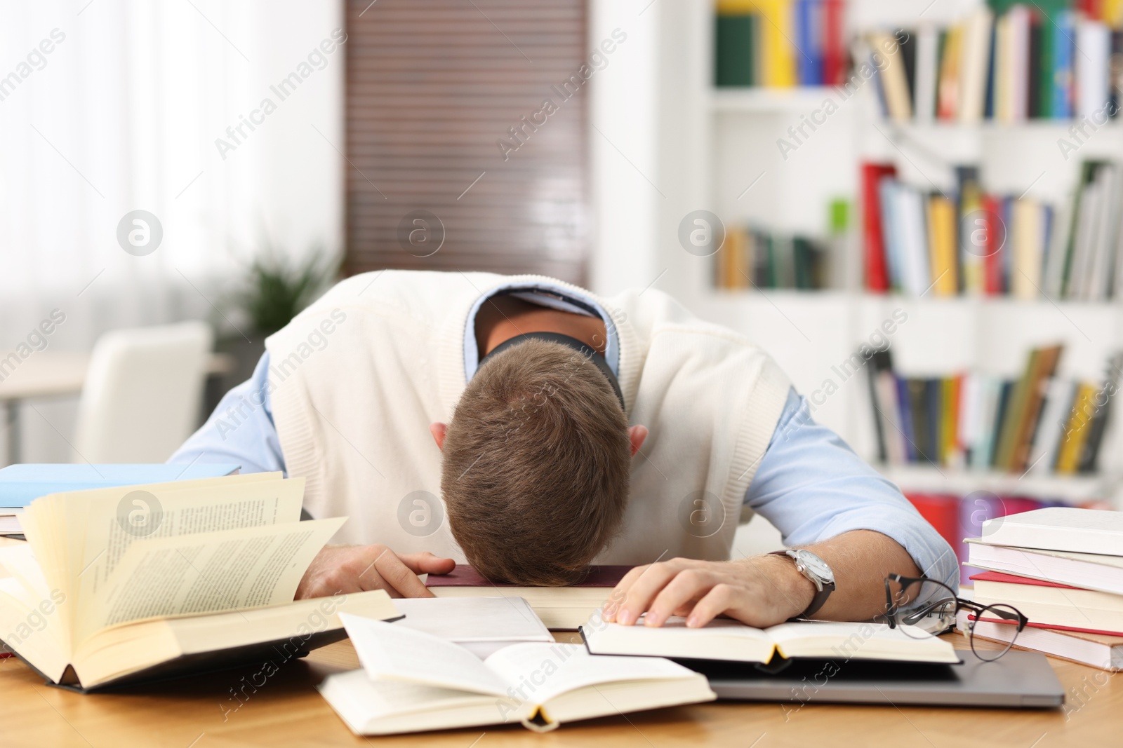 Photo of Preparing for exam. Tired student sleeping among books at table indoors