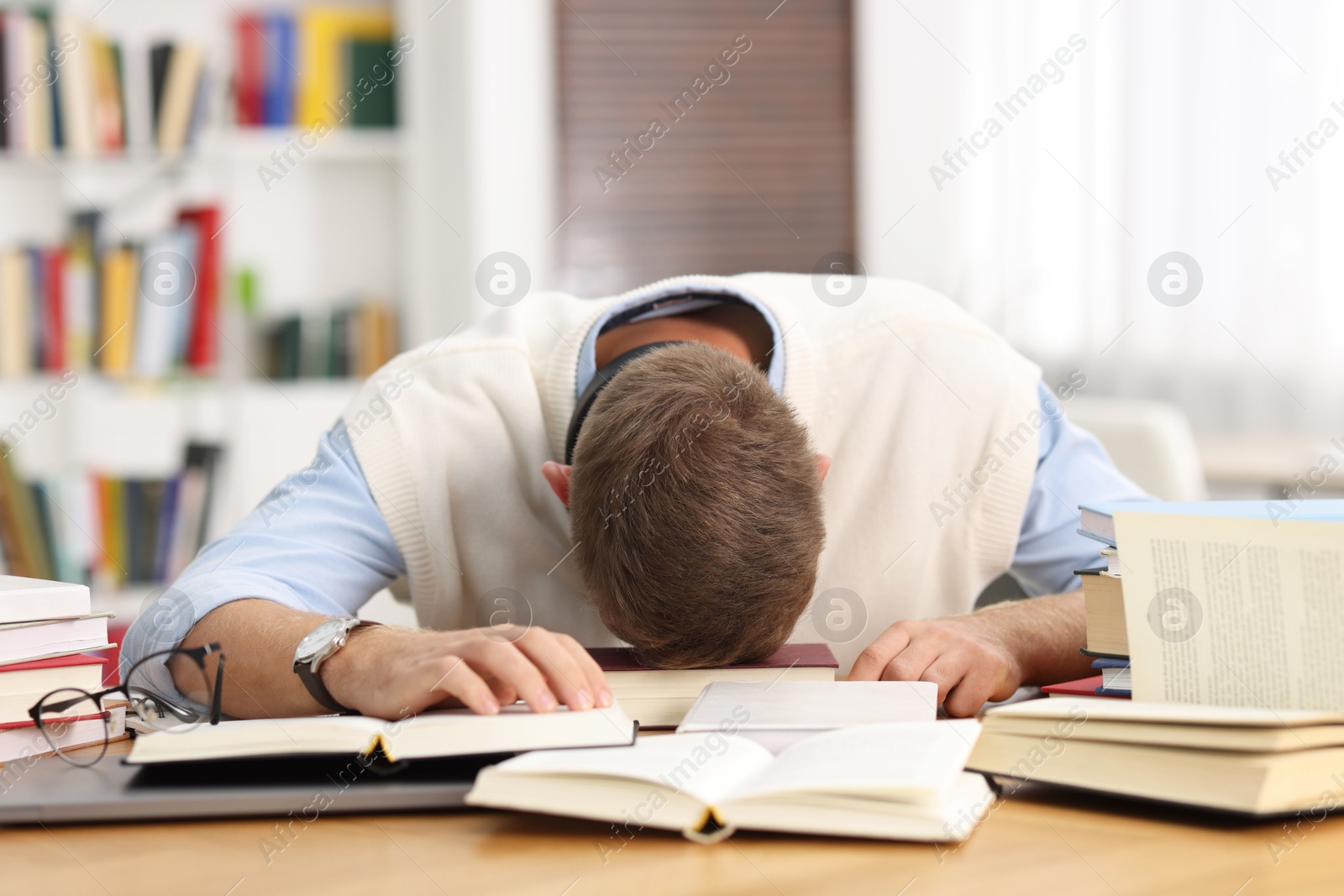 Photo of Preparing for exam. Tired student sleeping among books at table indoors