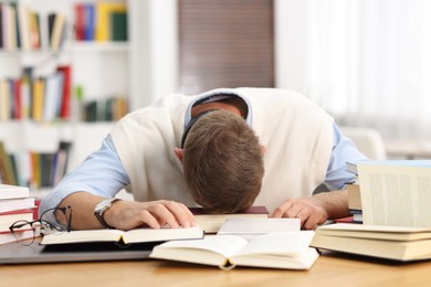 Photo of Preparing for exam. Tired student sleeping among books at table indoors