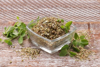 Photo of Dried oregano in glass jar and green leaves on wooden table, closeup