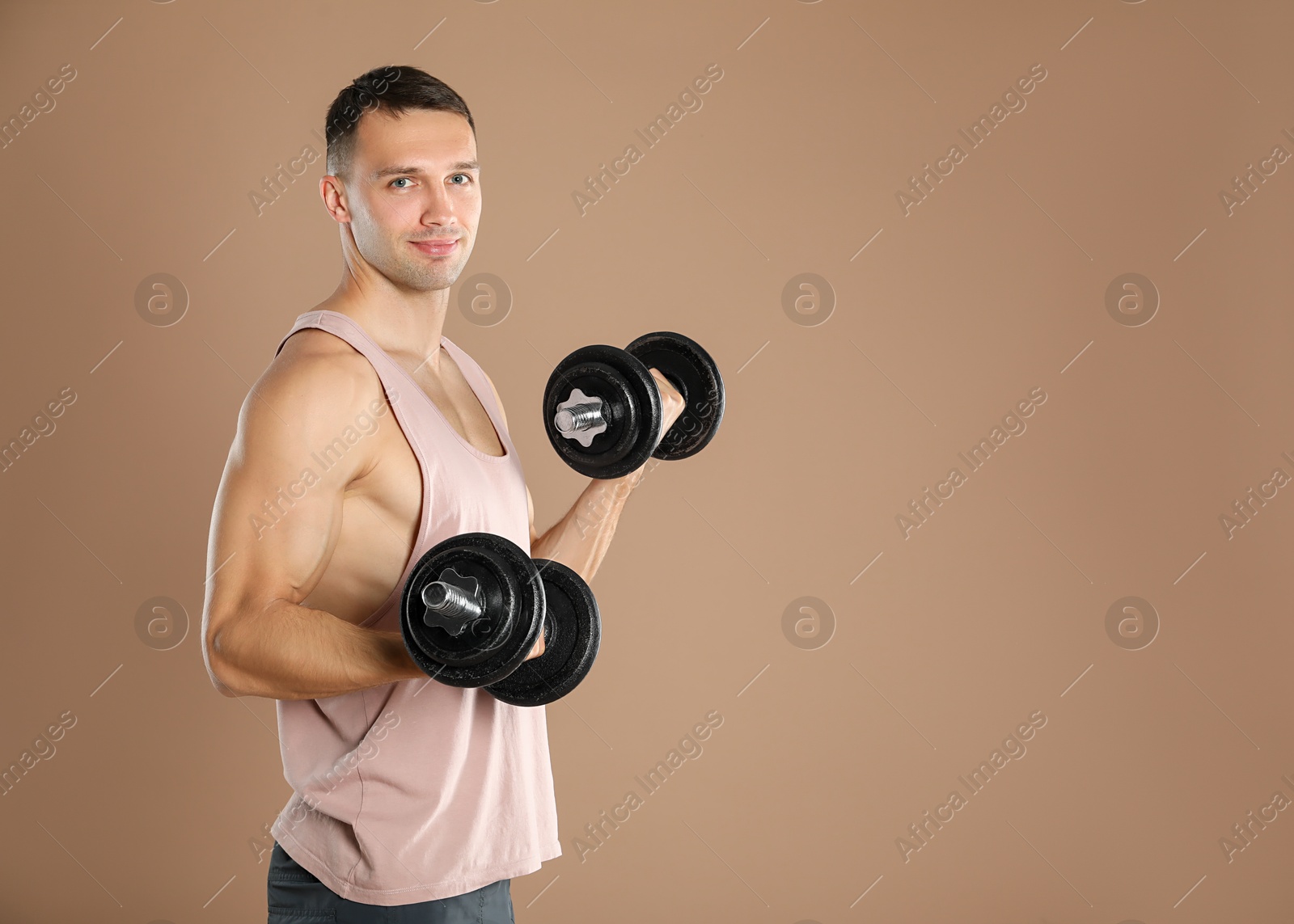 Photo of Man exercising with barbells on light brown background, space for text