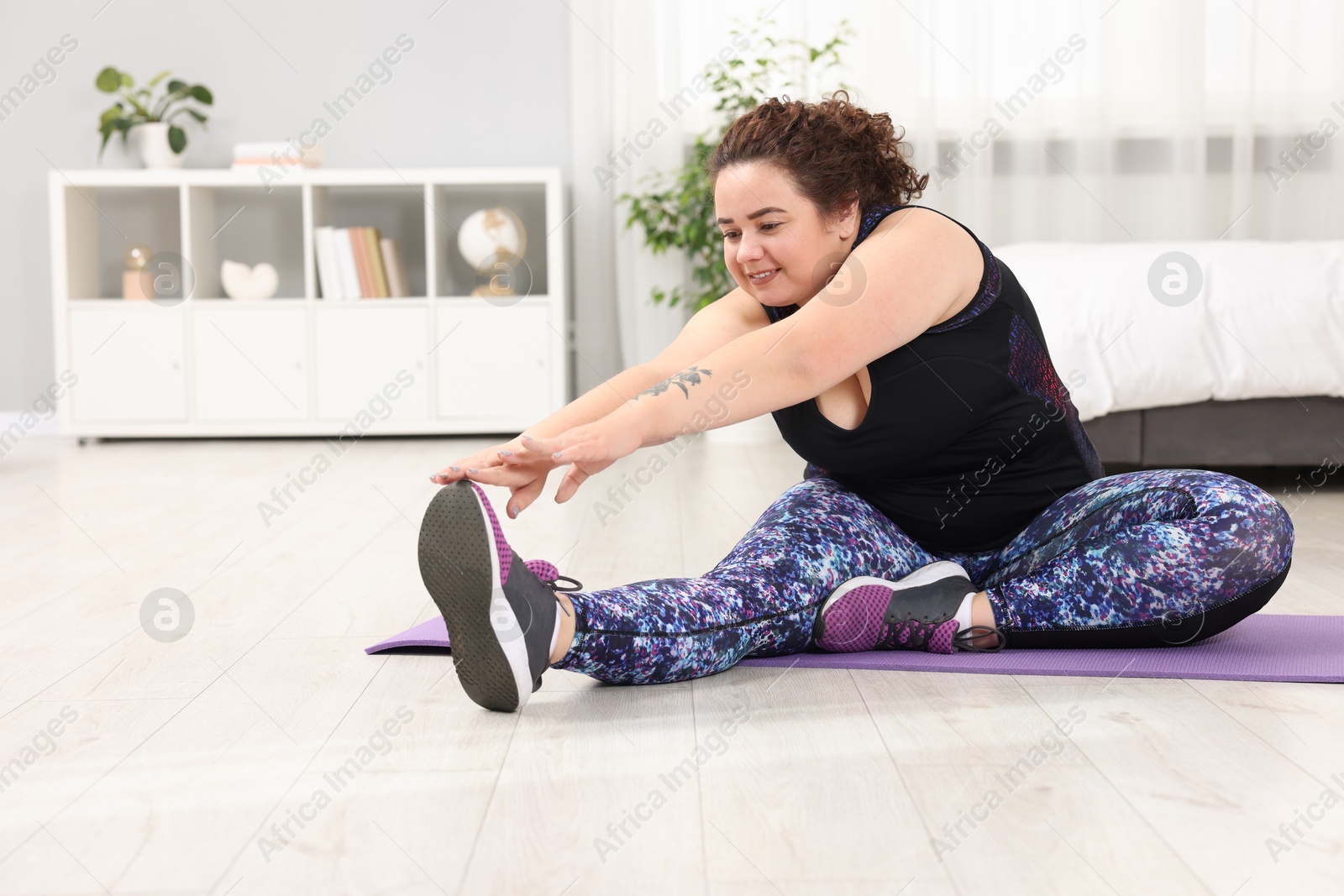 Photo of Plus size woman stretching during fitness training at home