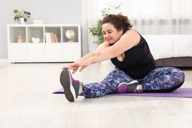 Photo of Plus size woman stretching during fitness training at home