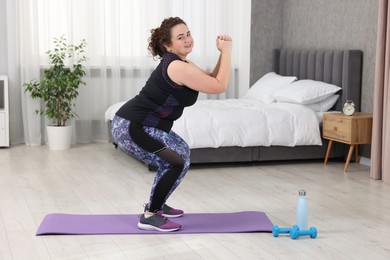 Photo of Plus size woman exercising on fitness mat at home