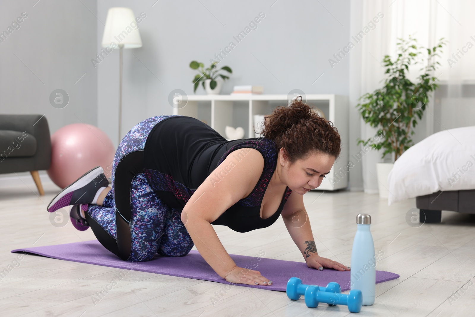 Photo of Plus size woman exercising on fitness mat at home