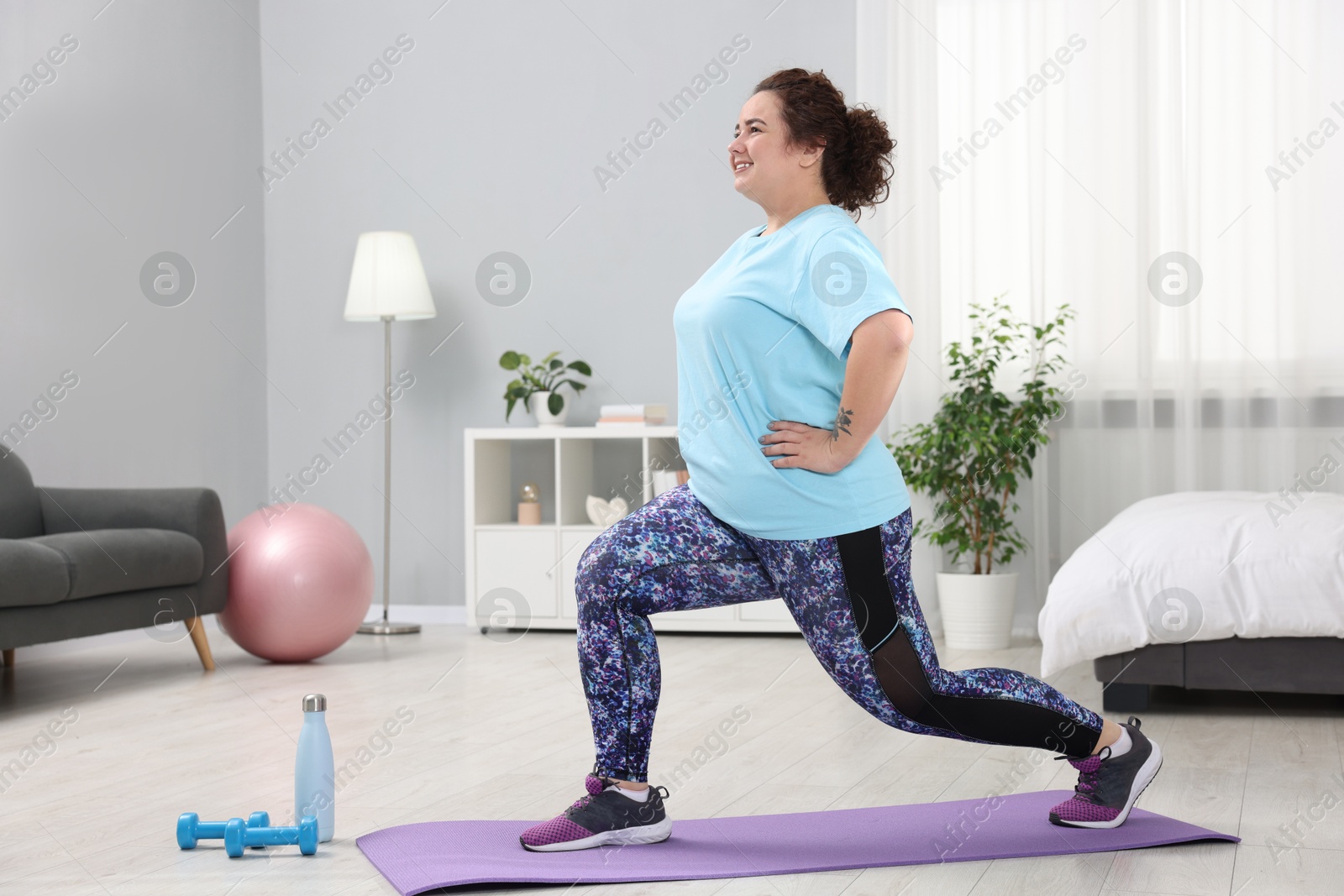 Photo of Plus size woman exercising on fitness mat at home