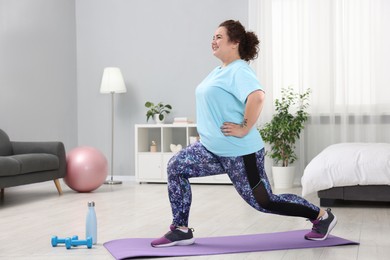 Photo of Plus size woman exercising on fitness mat at home