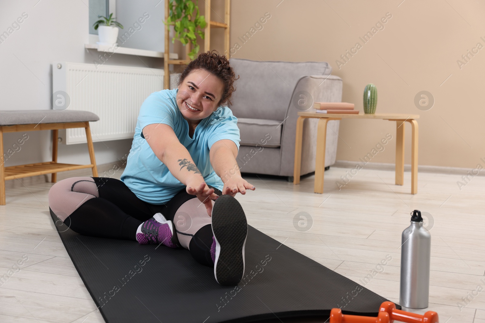 Photo of Plus size woman stretching during fitness training at home