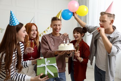 Photo of 18th birthday. Group of friends with tasty cake having coming of age party at home