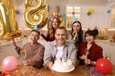 Photo of 18th birthday. Group of friends with tasty cake having coming of age party at home