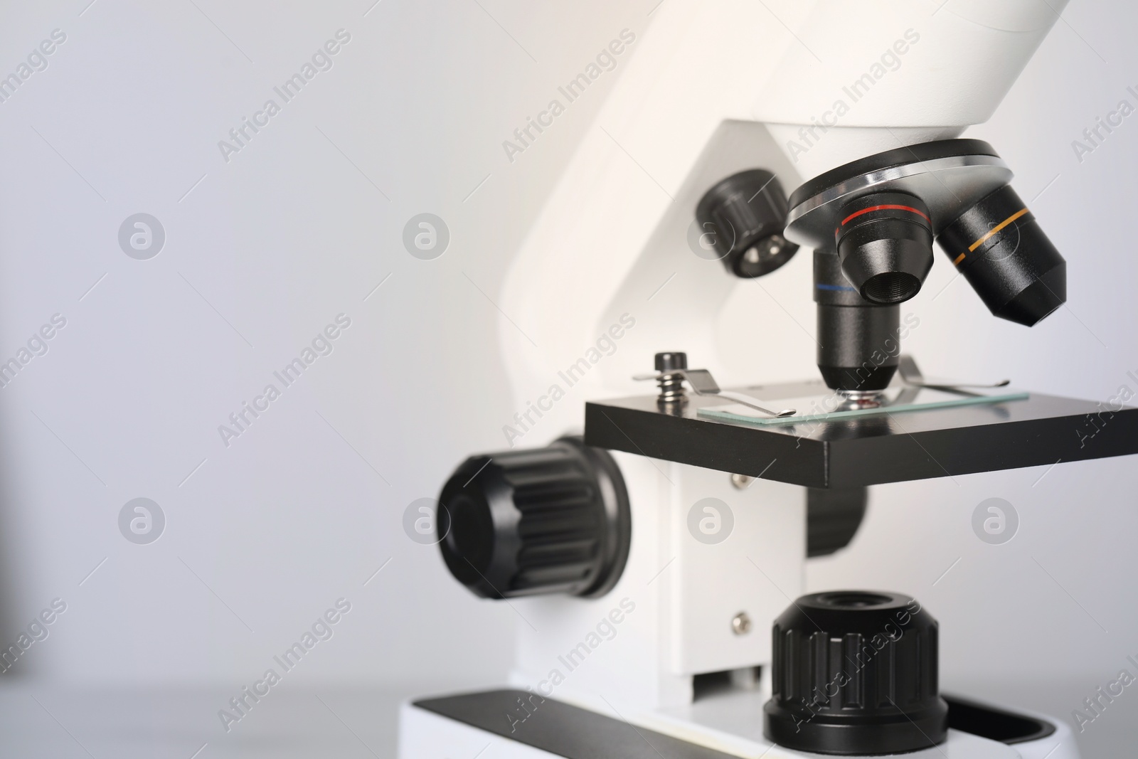 Photo of Science. Microscope with glass slide on light grey background, closeup. Space for text