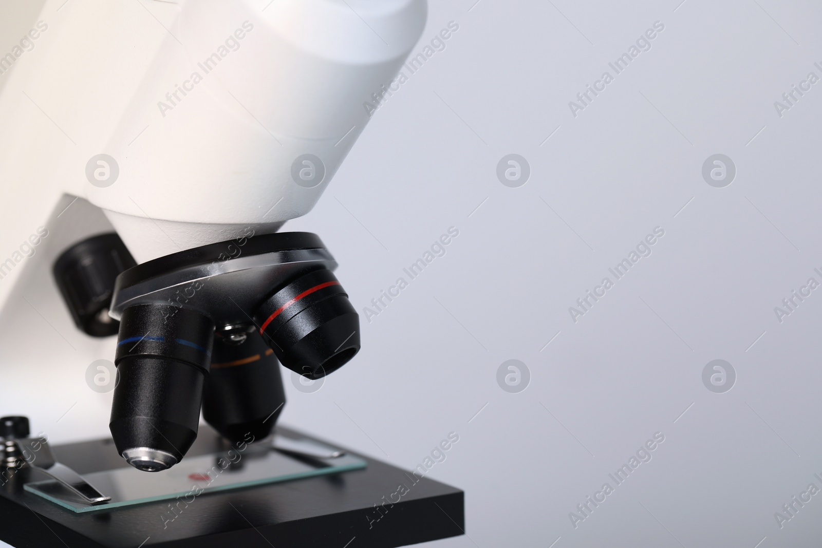 Photo of Science. Microscope with glass slide on light grey background, closeup. Space for text