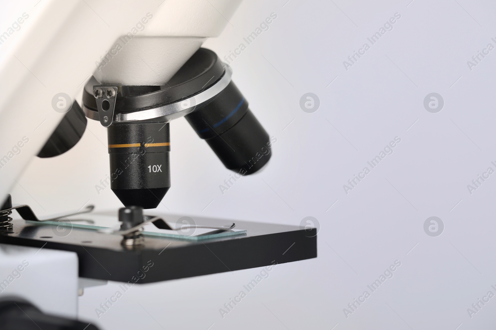 Photo of Science. Microscope with glass slide on light grey background, closeup. Space for text