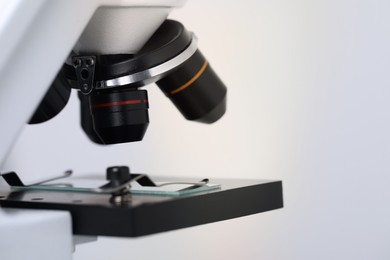 Science. Microscope with glass slide on light grey background, closeup