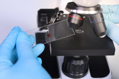 Photo of Scientist examining sample on slide under microscope, closeup