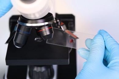 Scientist examining sample on slide under microscope, closeup