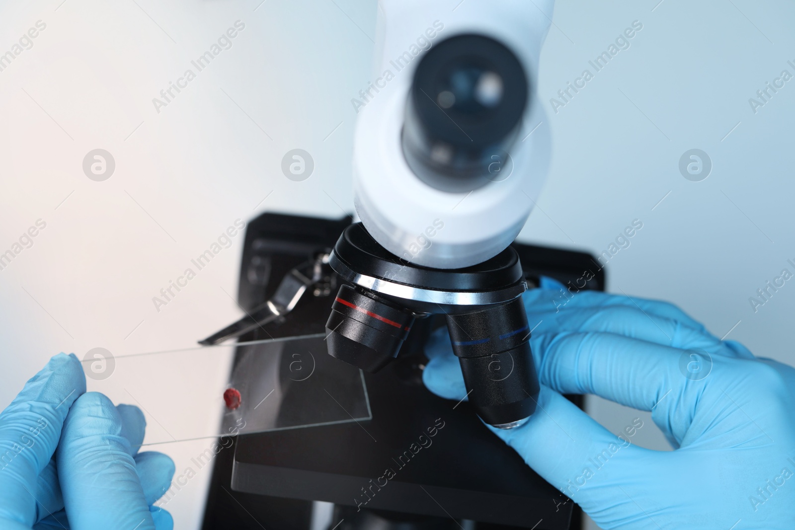 Photo of Scientist examining sample on slide under microscope, above view