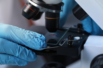 Photo of Scientist examining sample on slide under microscope, closeup