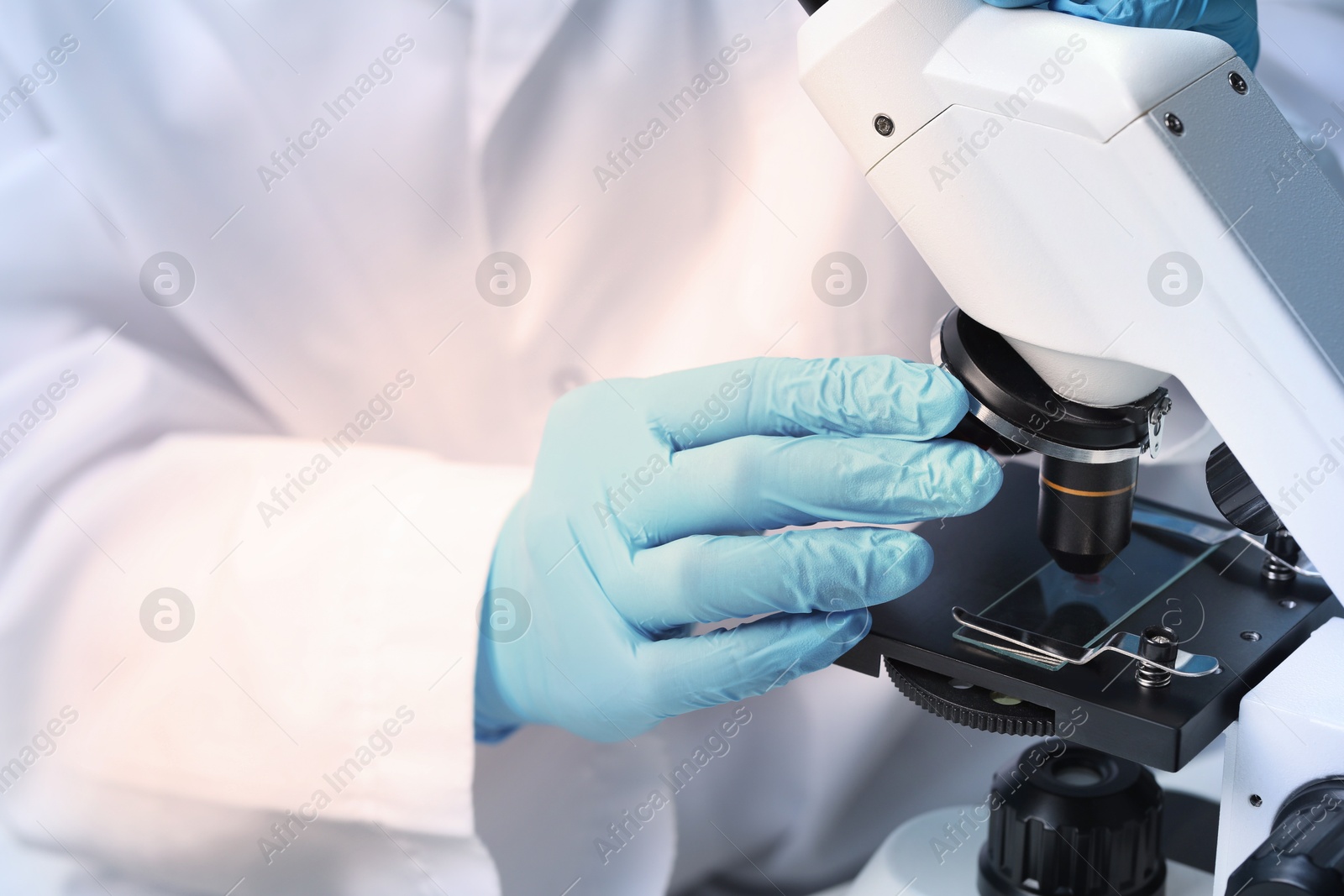 Photo of Scientist examining sample on slide under microscope, closeup