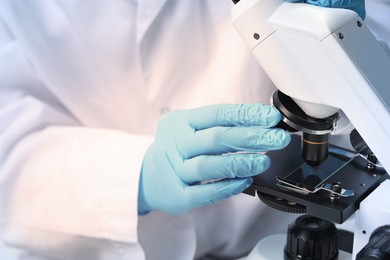 Scientist examining sample on slide under microscope, closeup