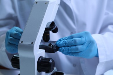 Scientist examining sample on slide under microscope, closeup