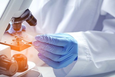 Scientist examining sample on slide under microscope, closeup