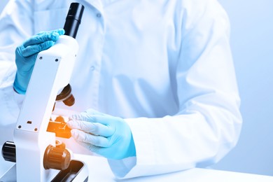 Scientist working with microscope in laboratory, closeup