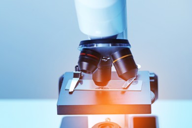 Photo of Science. Microscope with glass slide on blurred background, closeup