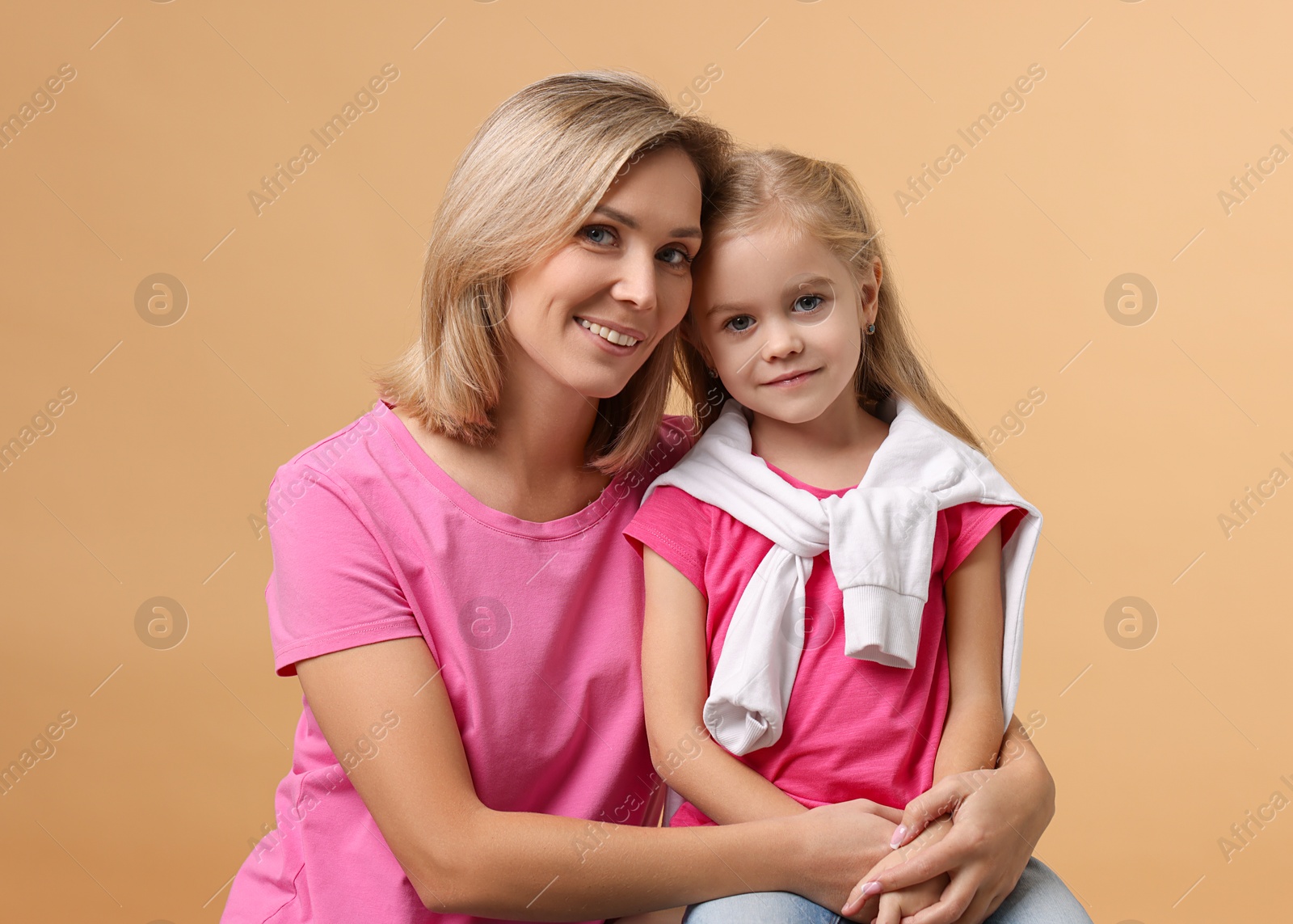 Photo of Cute little girl with her mom on beige background. Happy Mother's Day