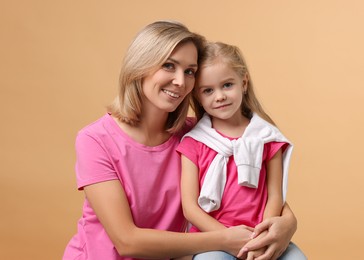 Photo of Cute little girl with her mom on beige background. Happy Mother's Day