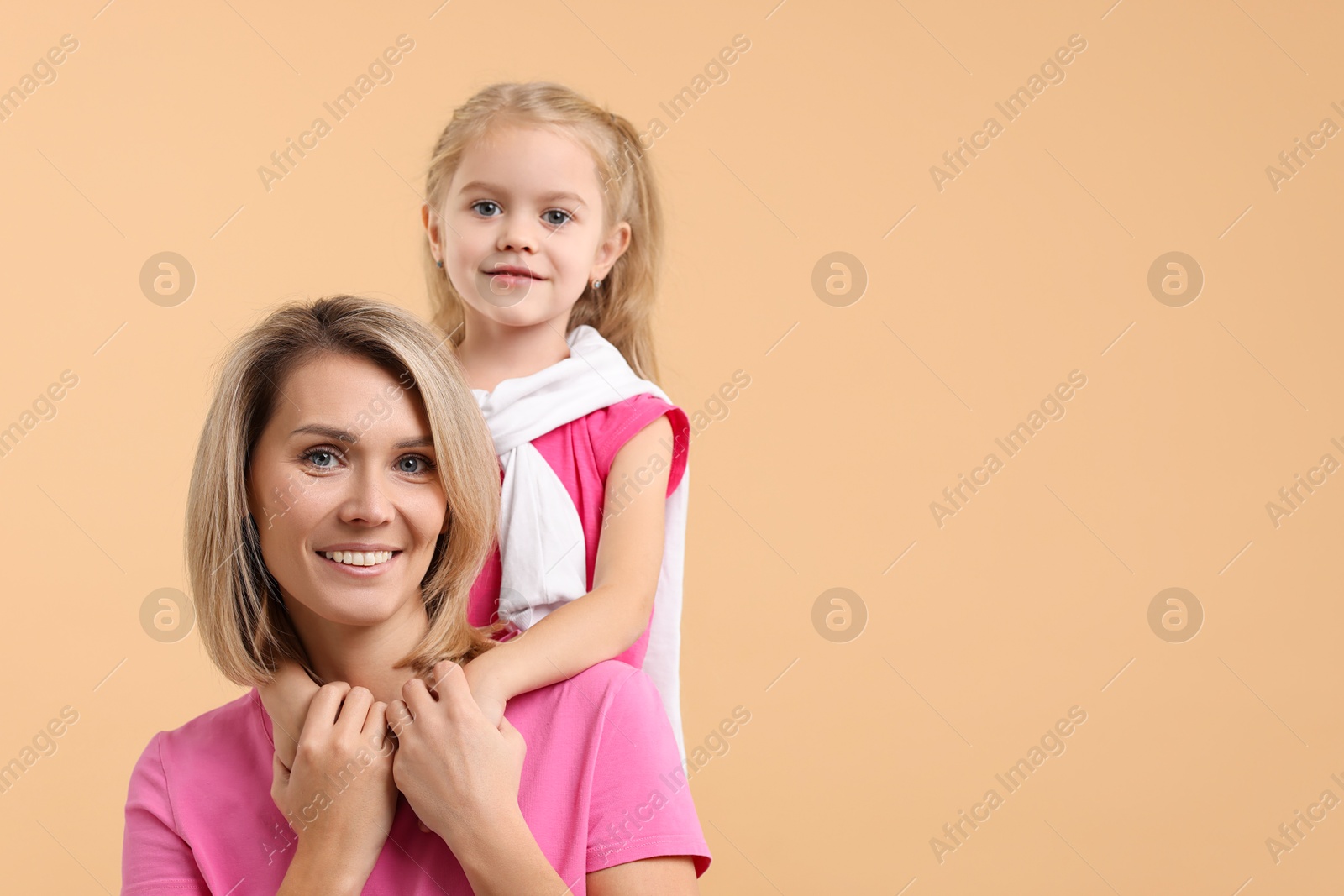 Photo of Cute little girl with her mom on beige background, space for text. Happy Mother's Day