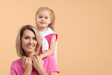 Photo of Cute little girl with her mom on beige background, space for text. Happy Mother's Day