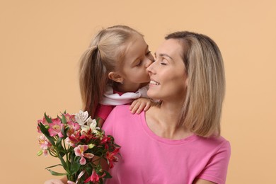 Photo of Little daughter congratulating her mom with bouquet of alstroemeria flowers on beige background. Happy Mother's Day