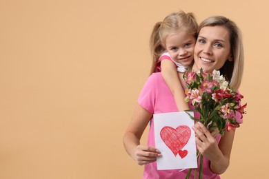 Happy woman with her daughter, bouquet of alstroemeria flowers and greeting card on beige background, space for text. Mother's Day celebration