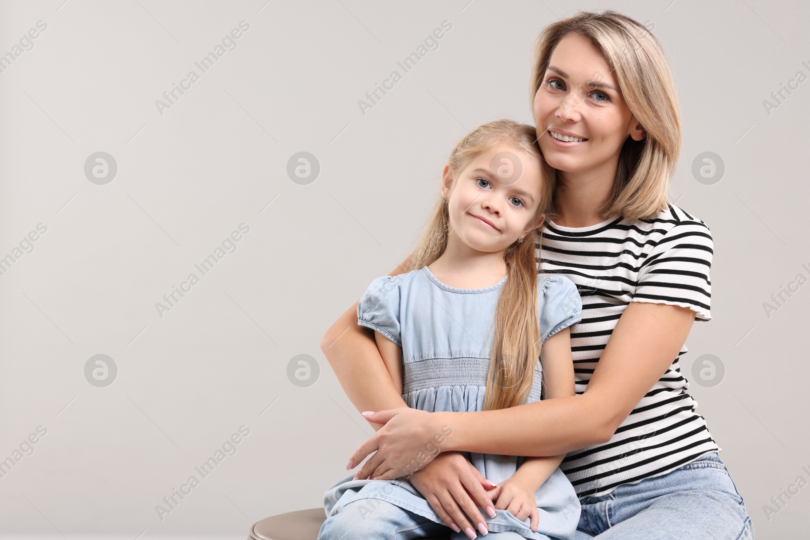 Photo of Cute little girl with her mom on gray background, space for text. Happy Mother's Day