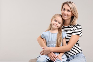 Photo of Cute little girl with her mom on gray background, space for text. Happy Mother's Day