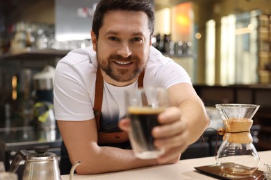 Photo of Barista suggesting cup of aromatic filter coffee in cafe, selective focus