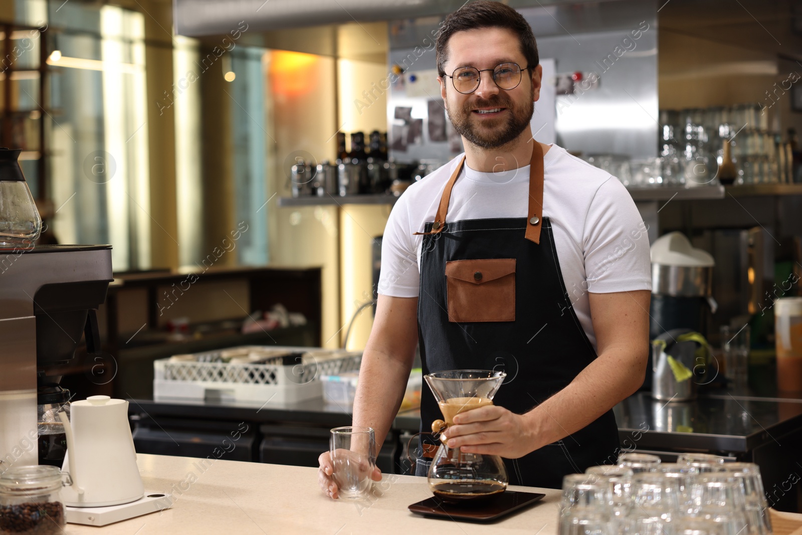 Photo of Barista with glass coffeemaker at table in cafe