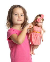 Photo of Cute little girl brushing doll's hair on white background