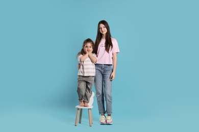 Photo of Portrait of cute sisters on light blue background