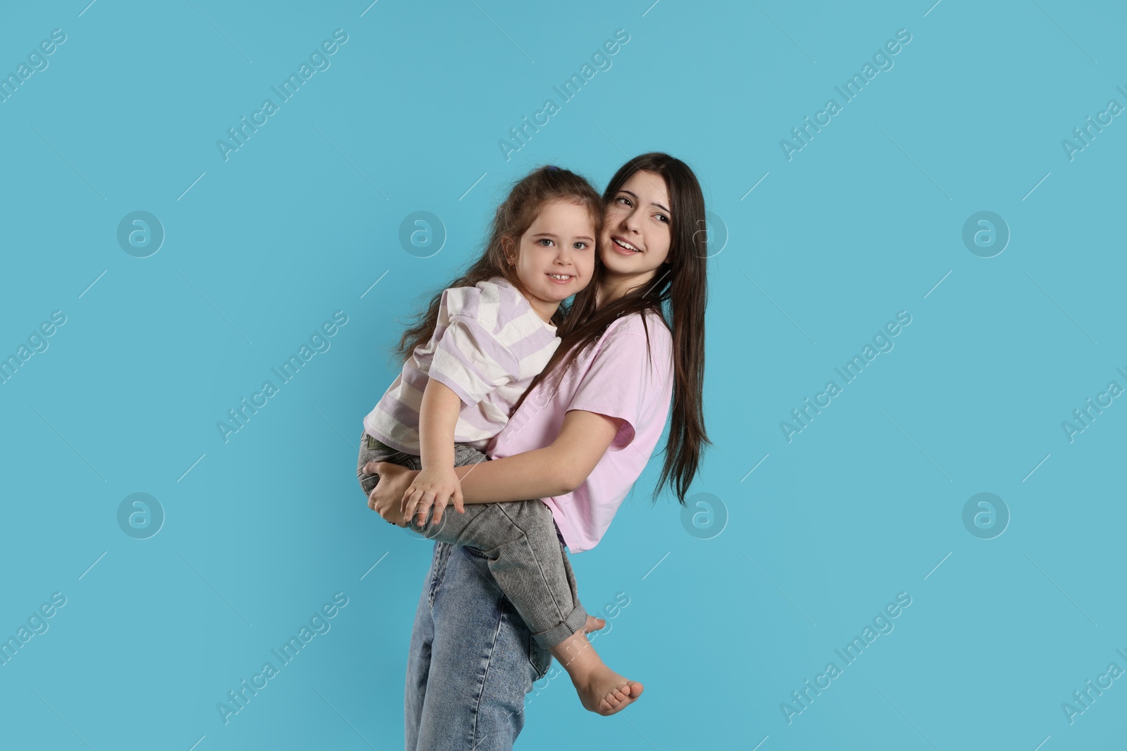 Photo of Portrait of cute sisters on light blue background