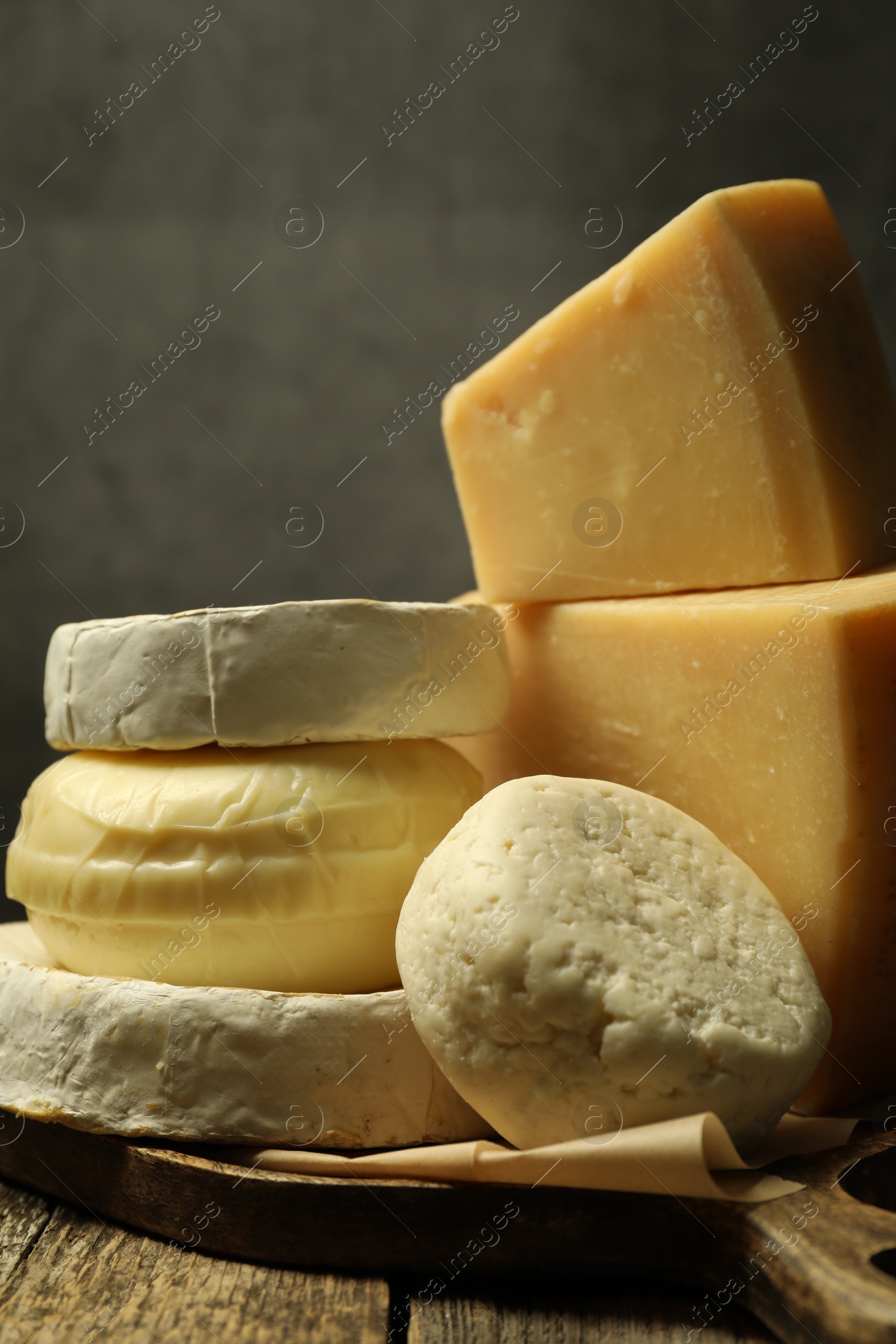 Photo of Different types of cheese on wooden table against grey background, closeup