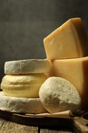 Photo of Different types of cheese on wooden table against grey background, closeup