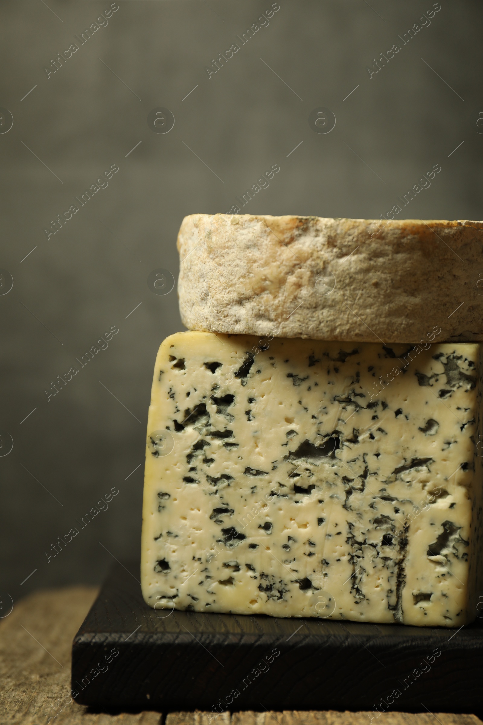 Photo of Fresh cheese on wooden table against grey background, closeup