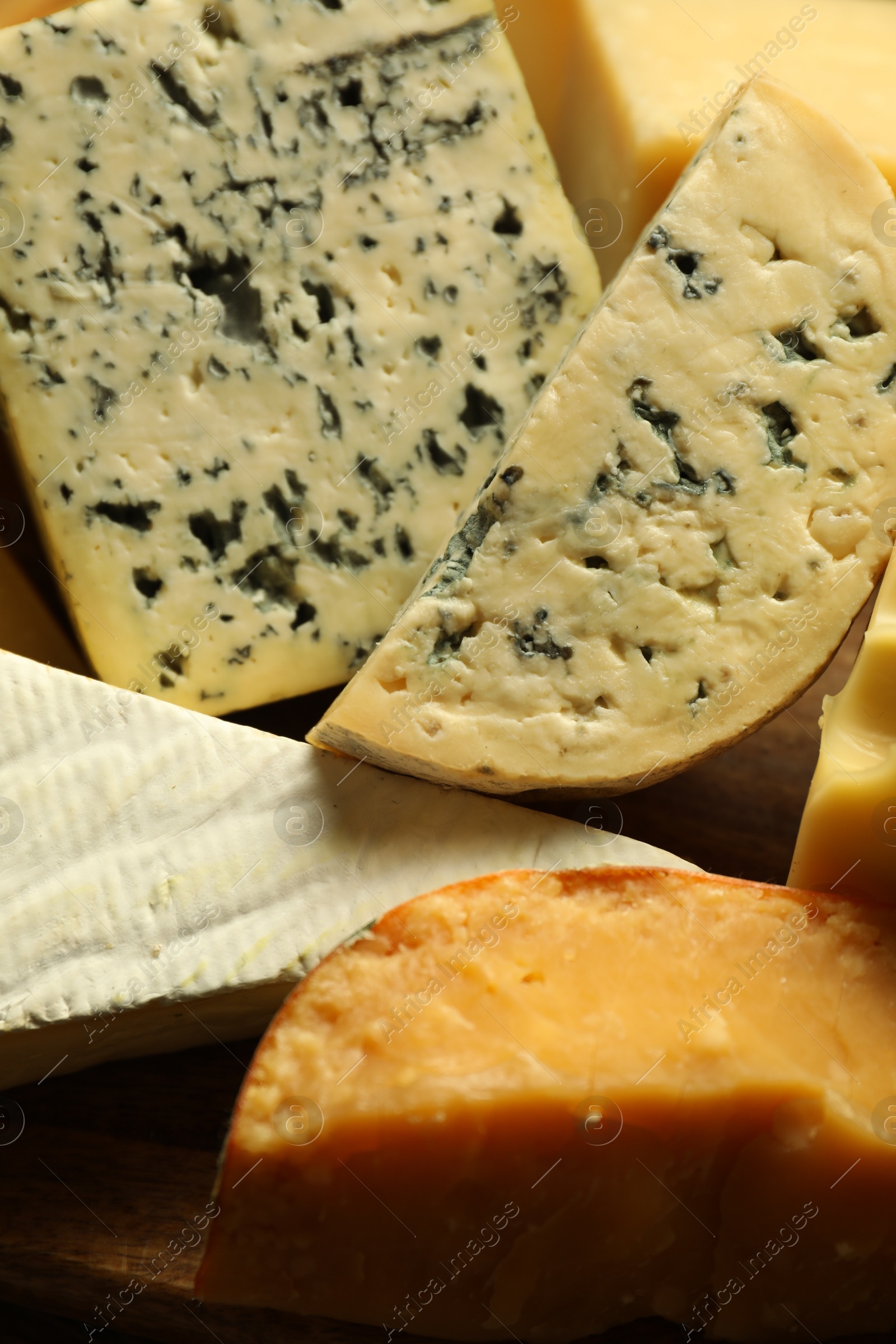 Photo of Different types of cheese on wooden table, closeup