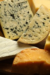 Photo of Different types of cheese on wooden table, closeup