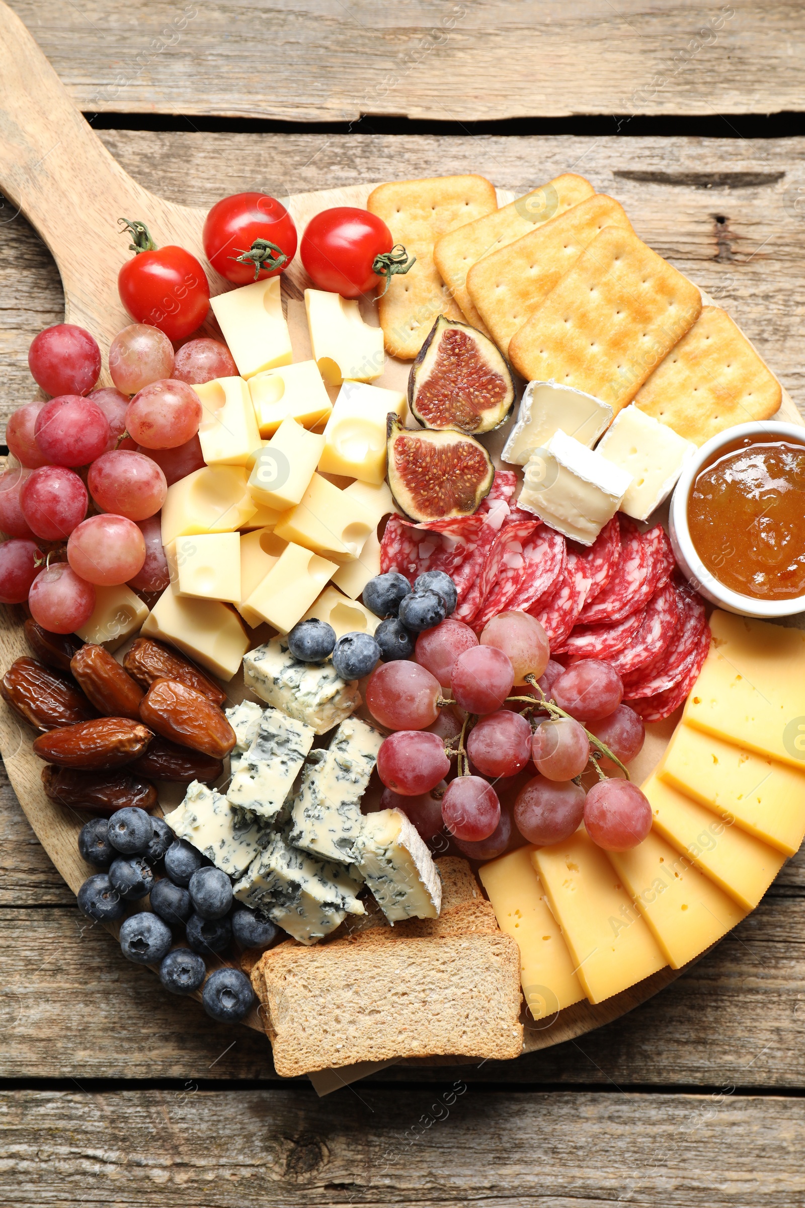 Photo of Different types of delicious cheese and other snacks on wooden table, top view